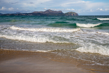 Mediterranean beach on the island of Majorca, or Mallorca on Balearic Sea, are part of Spain. Island in the Mediterranean Sea. Seaside vacations, clouds, seascape. View of the sea and the island.  