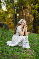 Fine art portrait of a young woman wearing light dress walking in a summer field with a basket of...