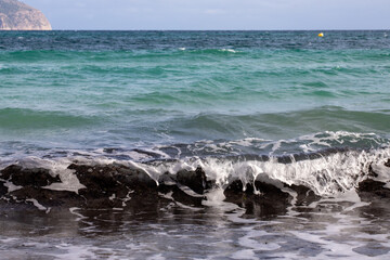 Obraz premium Mediterranean beach on the island of Majorca, or Mallorca on Balearic Sea, are part of Spain. Island in the Mediterranean Sea. Seaside vacations, clouds, seascape. View of the sea and the island. 