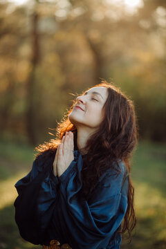 Woman praying with hands joined in nature during golden hour