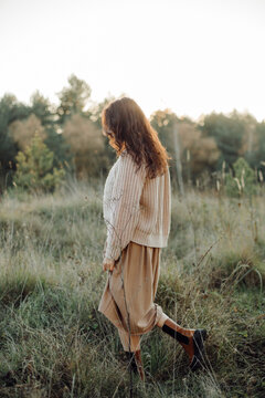 Woman strolling through serene meadow at sunset
