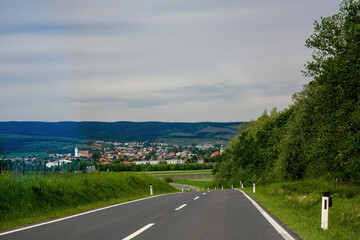 Country road leading to village with hills in background
