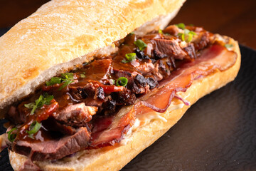 duck magret sandwich on italian baguette with bacon and spices macro close-up