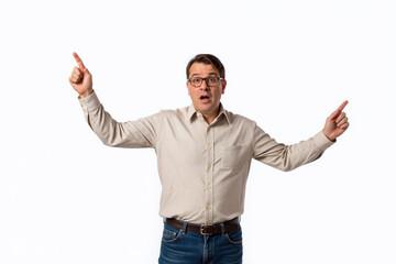 A man in a beige shirt and glasses, pointing upwards with both hands, looking surprised.