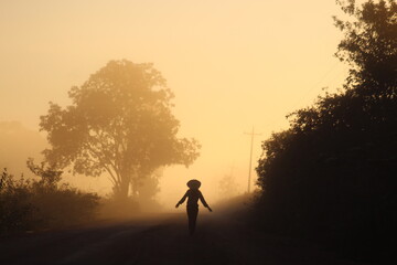 silhueta de mulher caminhando em estrada iluminada pelo nascer do sol. foto tirada na rodovia...