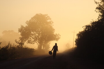 silhueta de mulher caminhando em estrada iluminada pelo nascer do sol. foto tirada na rodovia...