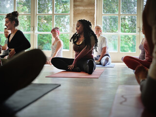 Woman, yoga and class or zen for spiritual wellness, body or workout together at gym or dojo. Calm female person, mentor or yogi people in easy pose for healthy exercise, fitness or mindfulness