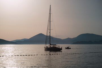 A Serene Sunset Featuring a Sailboat on Calm Waters Near Shore
