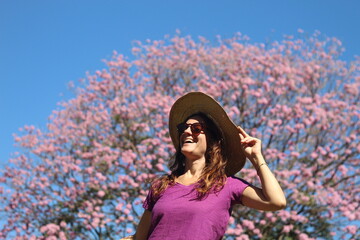 mulher em frente a ipê rosa florido em campo grande, mato grosso do sul 