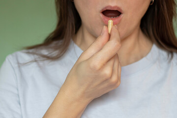 Naklejka premium A woman takes a capsule of vitamins or dietary supplements to maintain health