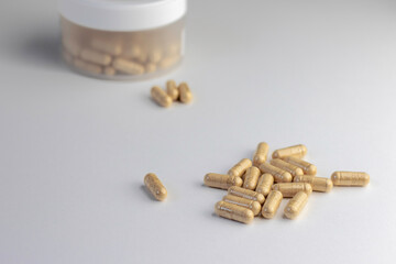 Vitamin capsules with beige powder inside close-up on white background. Biologically active...