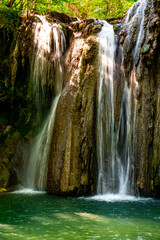 Hidden waterfall cascading through lush green forest in a serene natural oasis