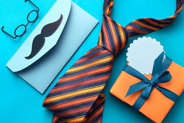 Father's day flatlay male objects top view on blue background.Tie orange gift box and...