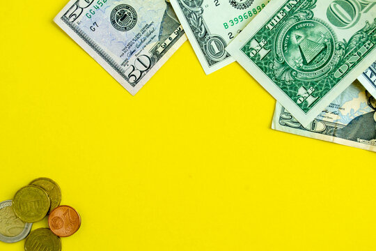 Dollars and euro coins on a yellow background, background with copy space.