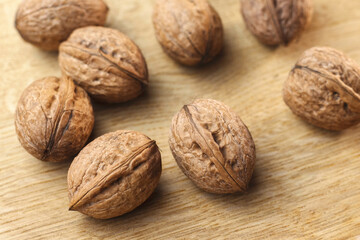 Close-up of walnuts in shell lying on wooden table surface. Selective focus. Super foods concept.