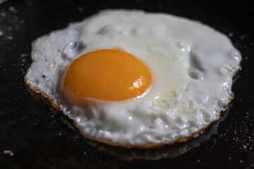 Fried egg - sunny side up cooking in a frying pan, close-up