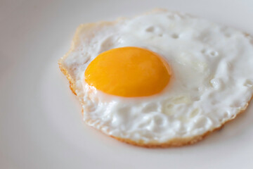 Appetizing fried egg - sunny side up on a white plate close-up. Quick and nutritious breakfast.