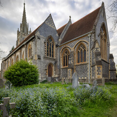 Side view of flint church showing stained glass and wildflowers.