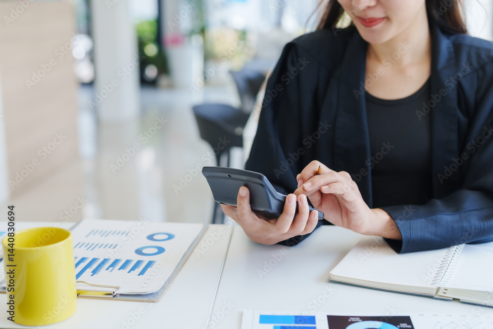 Poster businesswoman calculating financial indicators with a calculator while working at her desk in a mode