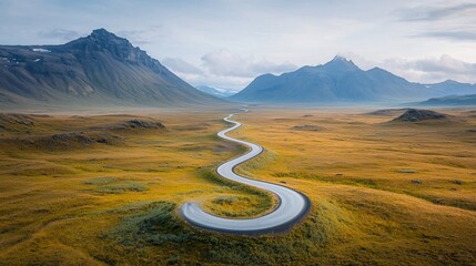 Winding road through a vast, golden landscape, leading to majestic mountains