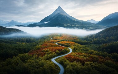 Winding road through autumnal valley, misty mountain peak