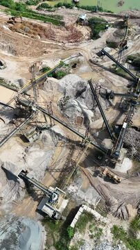 Vista a&eacute;rea vertical de planta de minera&ccedil;&atilde;o com britadores, esteiras e escavadeiras operando na extra&ccedil;&atilde;o e processamento de areia e brita em ambiente industrial a c&eacute;u aberto. Ind&uacute;stria pesada