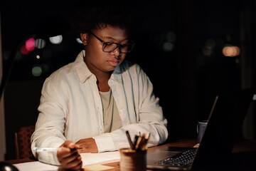 Young African businesswoman working at her office desk in the evening