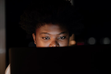 Young African businesswoman working on a laptop in her office late at night