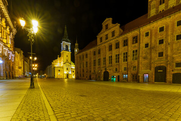 Night views of illuminated medieval city walls, gates and historic buildings in Toruń Old Town, Poland..