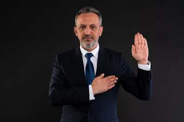 Businessman making an oath gesture with serious expression.