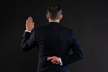 Businessman faking an oath with fingers crossed behind back.