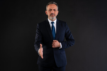 Businessman offering handshake in formal attire.