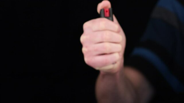 Hand holding a self-defense pepper spray device ready for use in a potential threat situation