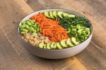 Vegan Poke bowl with quinoa,  edamame beans, cucumber and carrots in a gray bowl. Hawaiian ahi poke bowl, gray background.