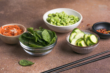 Vegan poke bowl ingredients with beans, spinach, cucumber, carrots and mangoes. Vegan food concept.