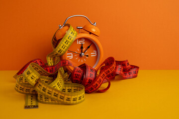 Alarm clock with measuring tapes, copy space. Healthy lifestyle, weight loss 
