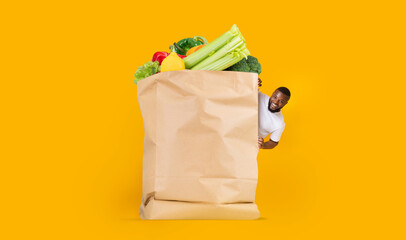 A customer joyfully engages with a large paper bag full of fresh vegetables and fruits. The vibrant...