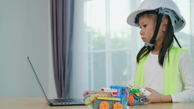 Kid playing with construction blocks on table and hands typing on laptop computer, child playing and building with colorful plastic bricks. Early learning and development.