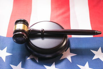 Gavel and base resting on American flag representing legal justice and democracy in a courtroom setting
