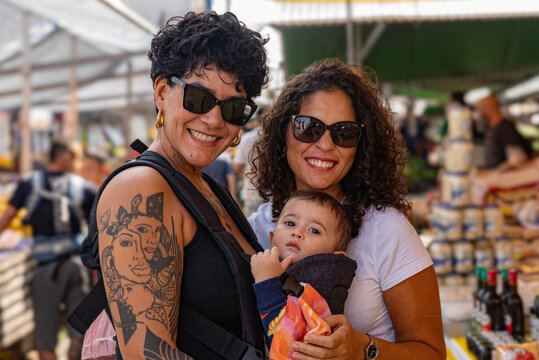 Portrait of Brazilian lesbian couple and baby at a street market in S&atilde;o Paulo