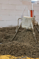 A construction site featuring a concrete mixer on aggregate material, light colored concrete block...