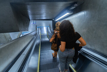 Overhead view of women on São Paulo subway escalator, one with baby carrier