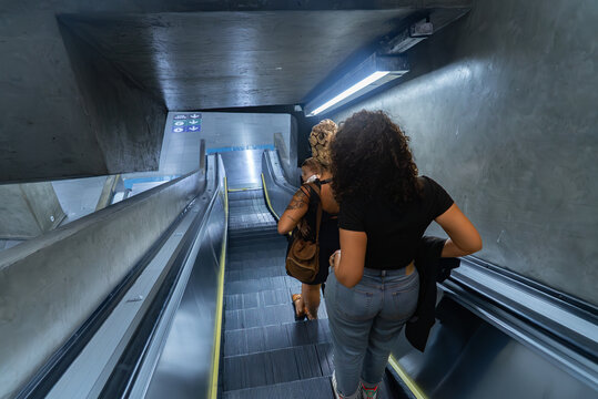 Overhead view of women on São Paulo subway escalator, one with baby carrier - Powered by Adobe