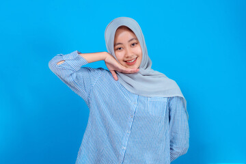 Young Asian Muslim woman wearing a light gray hijab and striped shirt smiling sweetly while resting...