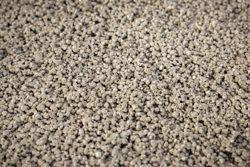 A detailed view of small, uniformly sized granules in light gray, showcasing a rough texture. The material appears suitable for construction use.