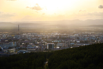 View from the mountain to the city located in the valley and the mountains at sunset. Beautiful city landscape of Sakhalin