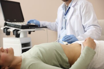 Sonographer conducting woman's abdominal ultrasound examination in clinic, closeup
