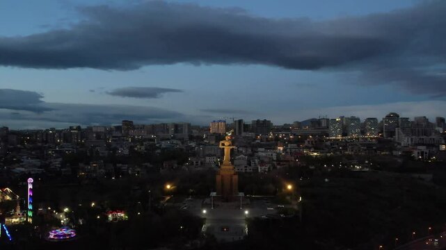 Yerevan, Armenia &ndash; April 16, 2025: Aerial night view of the Mother Armenia statue illuminated in Victory Park against the backdrop of the city lights.