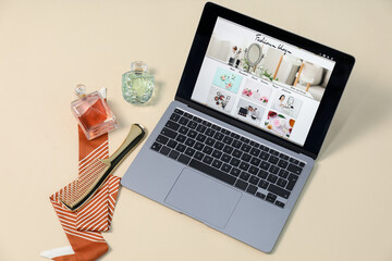 Laptop with fashion blog web site, accessories and perfumes on beige background, above view