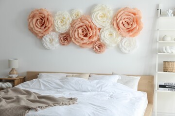 Fototapeta premium Beautiful decorative paper flowers on wall in bedroom